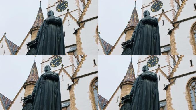 罗马尼亚锡比乌的乔治·丹尼尔·特伊施主教雕像。背景上的锡比乌·路德教会大教堂