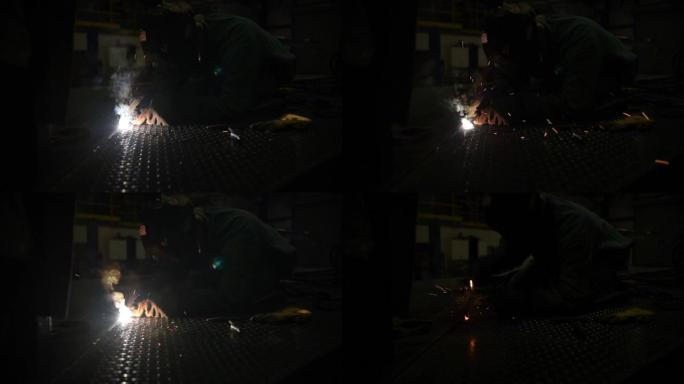 焊工在带有发光金属的钢料上制作焊接线的侧视图