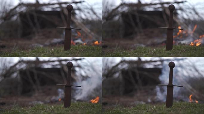 生锈的剑在火的背景下在地面上