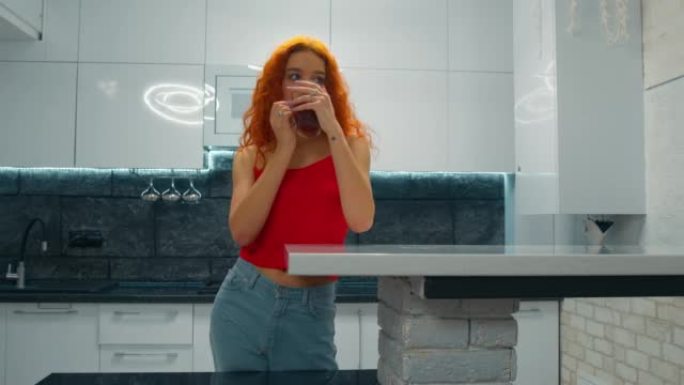红头发的年轻女子在厨房喝茶