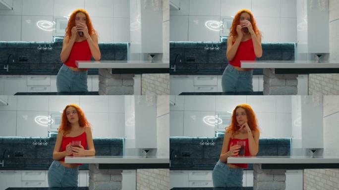 红头发的年轻女子在厨房喝茶