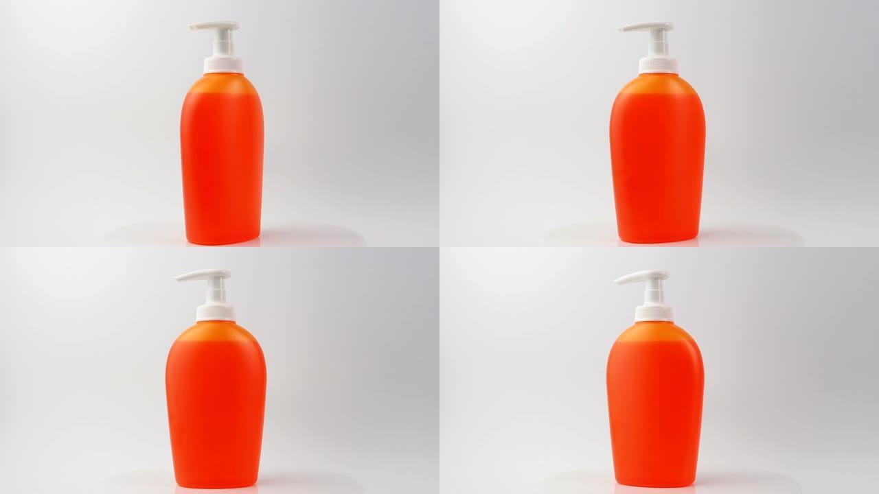 特写，橙色肥皂分配器和液体肥皂。带凝胶的彩色瓶