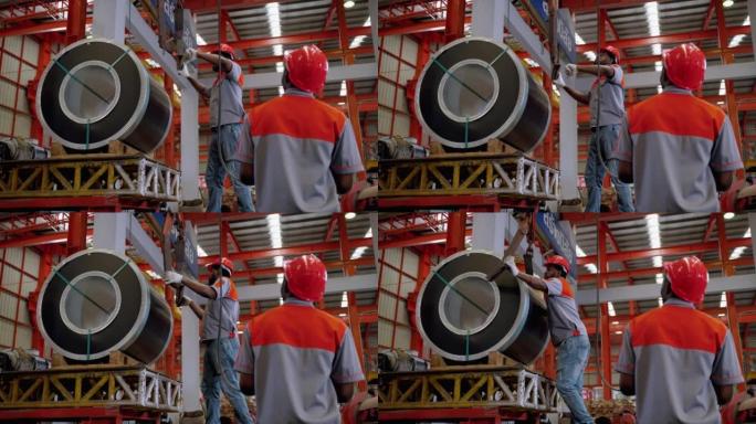 非裔美国人的工人正在使用提升机和起重机来提升钢铁或要在工厂中分类的货物。