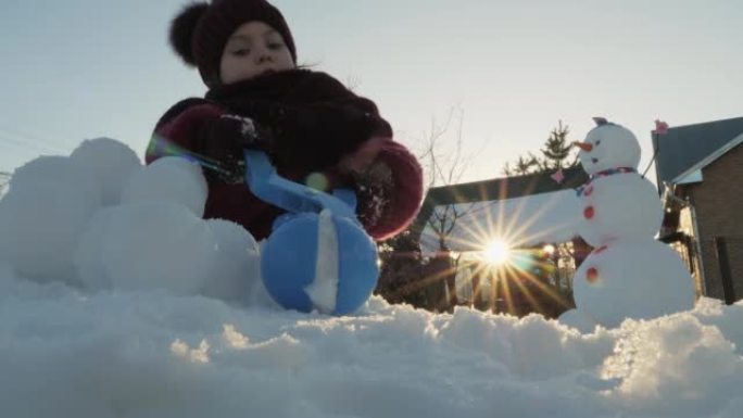 女孩在日落的灯光下做雪球。