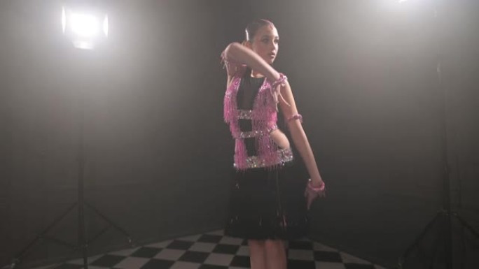 穿着漂亮的粉色黑色连衣裙的迷人少女专业舞蹈舞厅体育舞蹈桑布拉丁美洲人在充满烟雾的黑暗房间里跳舞