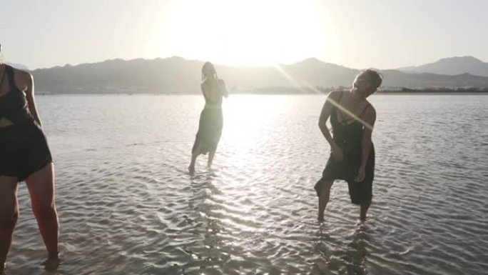 一群潮湿迷人的女性在日落慢动作时在海上狂喜跳舞