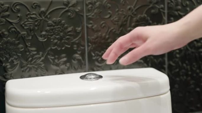 手按下马桶上的冲洗按钮。节水。卫生概念。