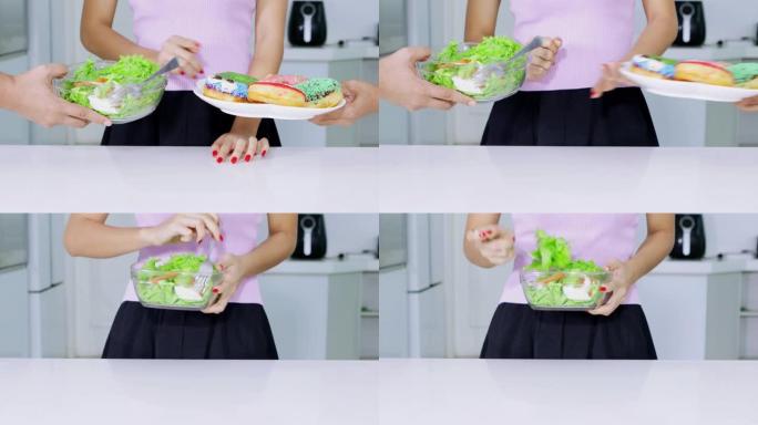 节食概念。不知名的女人手势拒绝一盘甜甜圈，选择一碗沙拉。以4k分辨率拍摄