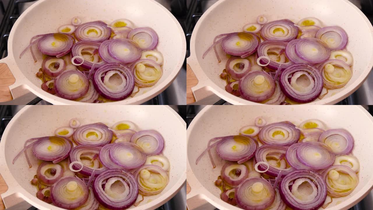 用加热的橄榄油在白色煎锅中油炸切成薄片的紫色洋葱特写放大
