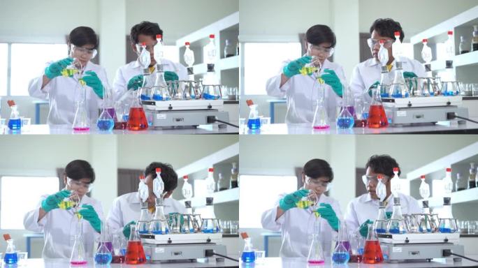 一组亚洲医学科学家研究人员穿着实验室外套和防护设备，在寻找潜在的新型冠状病毒肺炎疫苗时，仔细检查，测