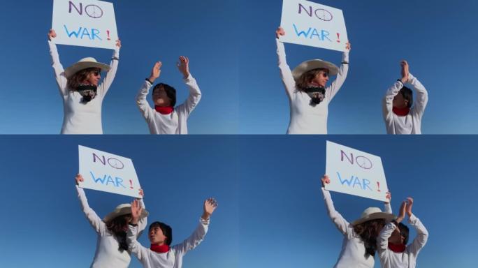 一位积极分子的母亲和她的亚裔儿子用蓝色天空背景上的“不战争”标志抗议战争。世界和平和没有战争的概念