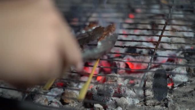 特写街头食品销售商正在烤串上烧烤牛肉。
