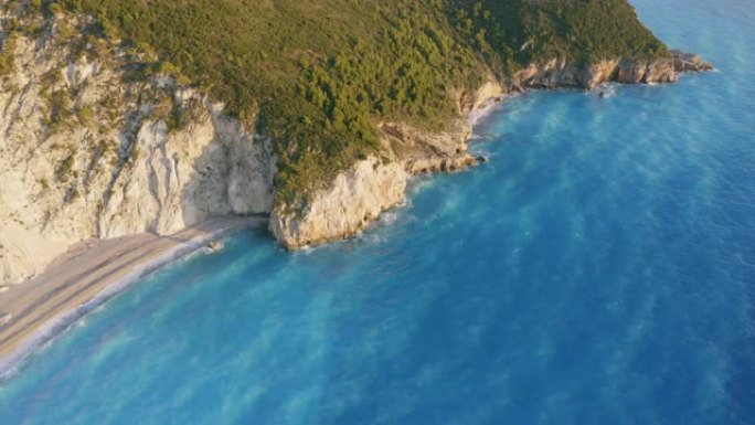 希腊爱奥尼亚岛莱夫卡达美丽的米洛斯海滩鸟瞰图。日落金色的阳光，悬崖海岸线和原始的海浪打破了岸边的碧蓝