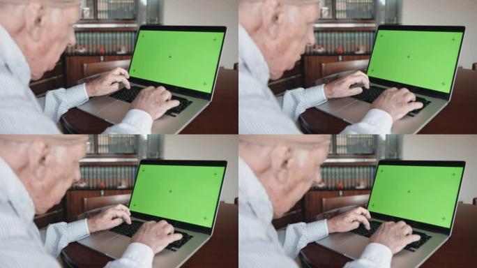 老人用绿屏色度键慢慢在电脑键盘上打字，养老金领取者通过笔记本电脑浏览互联网。孤独的人在电脑上搜索信息