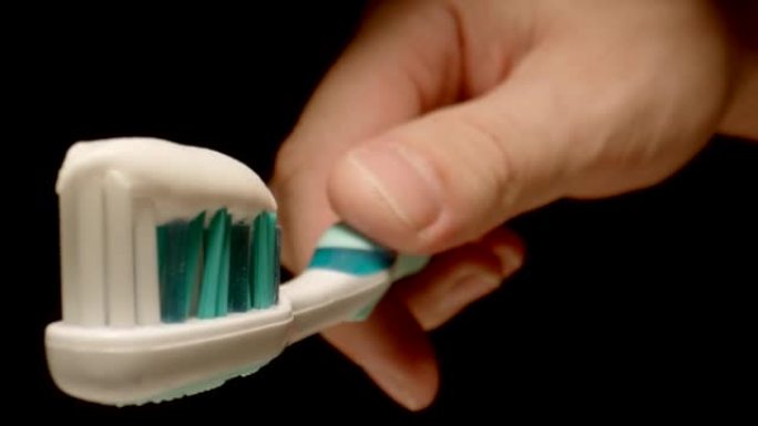 宏观: 男性手中的牙刷上的牙膏