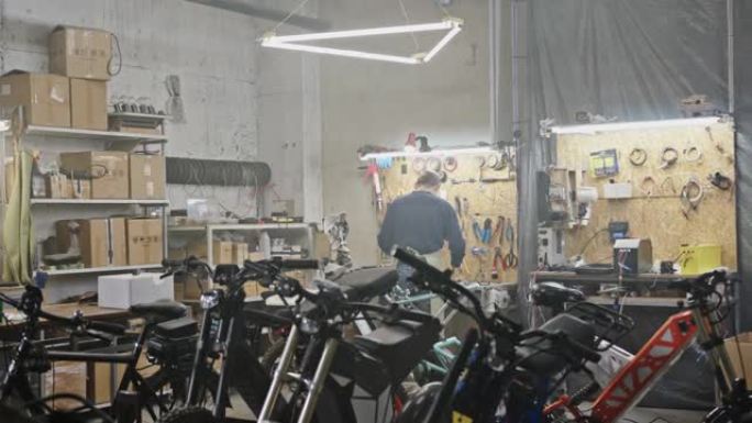 在车库工作的面目全非的人。在宽敞的车间里，匿名男子机械师站在自行车和摩托车后面的工作台附近