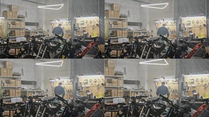 在车库工作的面目全非的人。在宽敞的车间里，匿名男子机械师站在自行车和摩托车后面的工作台附近