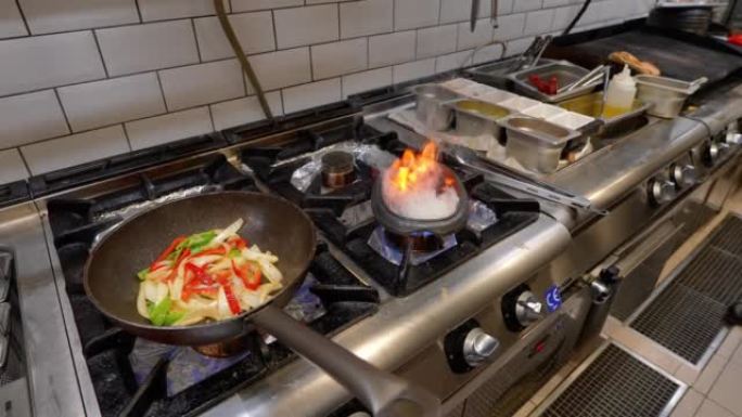 在铸铁锅中煮熟的蔬菜和不断上升的火焰