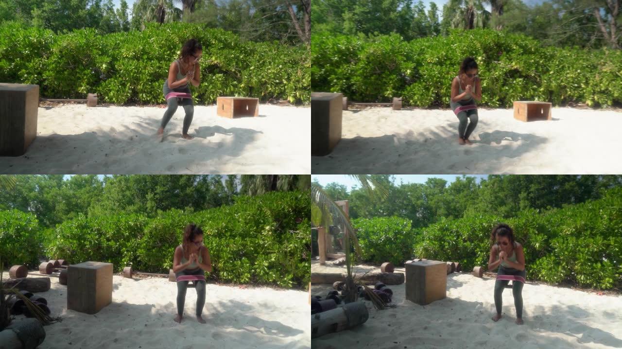 年轻的西班牙裔妇女在生态海滩健身房用松紧带蹲下