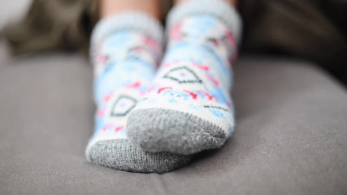 女人在冬季羊毛袜子中移动脚，特写，粉色毯子
