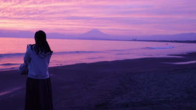 日落时分，女人在海滩上看着风景