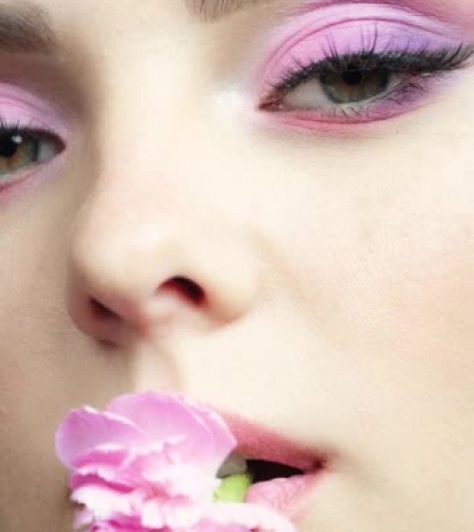 特写慢动作垂直视频，女性嘴里有粉红色康乃馨。