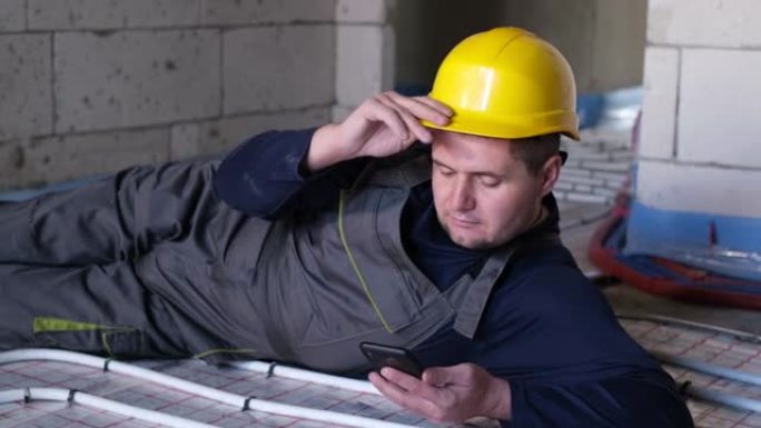 水管工手里拿着智能手机休息，测量智能手机的工作量。