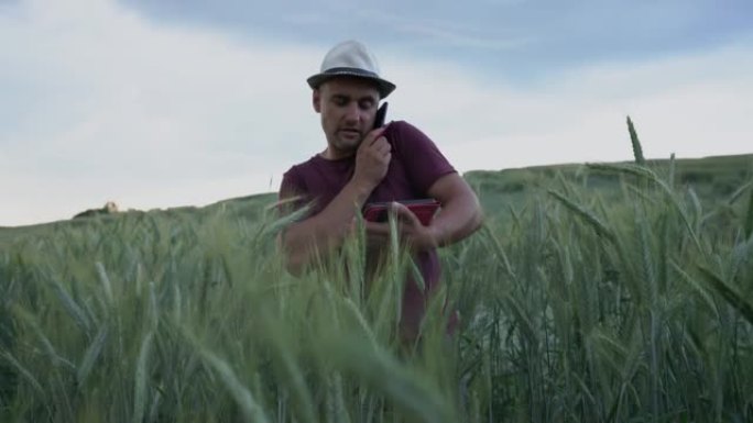 帽子上的男人农艺师拿着平板电脑，结束电话通话