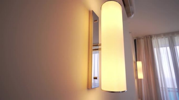 壁灯挂在酒店或公寓的白色墙上。有人关灯