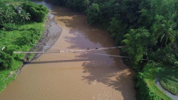 无人机拍摄了在一条大河上建造的木制吊桥，作为村民进出村庄的通道