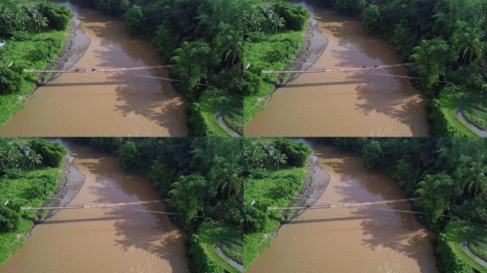 无人机拍摄了在一条大河上建造的木制吊桥，作为村民进出村庄的通道