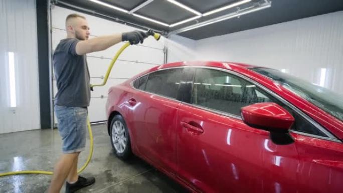 用泡沫和高压水清洗洗车。红色汽车