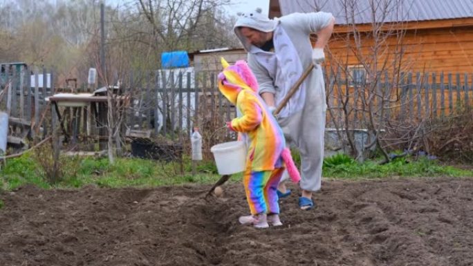 穿着独角兽服装的孩子帮助农民在花园里种土豆