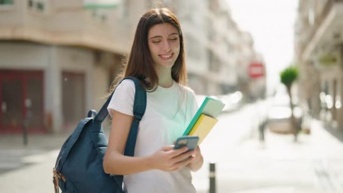 年轻的西班牙裔女学生在街上使用智能手机微笑着自信