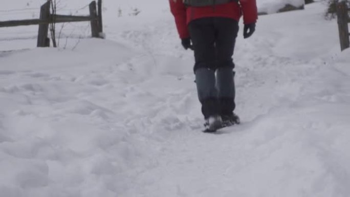 冬天的男人脚温暖舒适的鞋子在冬天的公园里的雪道上迈出一步。