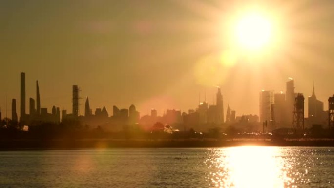 日出从水面反射，曼哈顿天际线剪影建筑天际线。