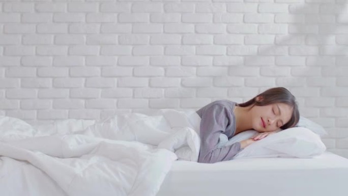 美丽迷人的亚洲女人早上躺在舒适的卧室的床上睡觉和甜蜜的梦，感觉如此放松和舒适。健康的年轻女性在家睡觉