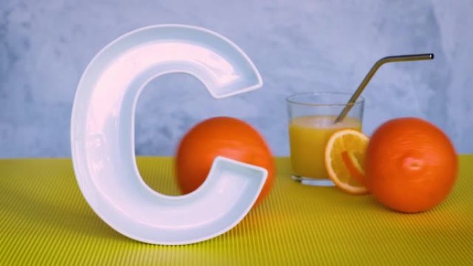 食品概念中的维生素c。字母C形状的盘子，鲜榨的橙汁和两个滚动的橙子。抗坏血酸对免疫系统功能很重要。循