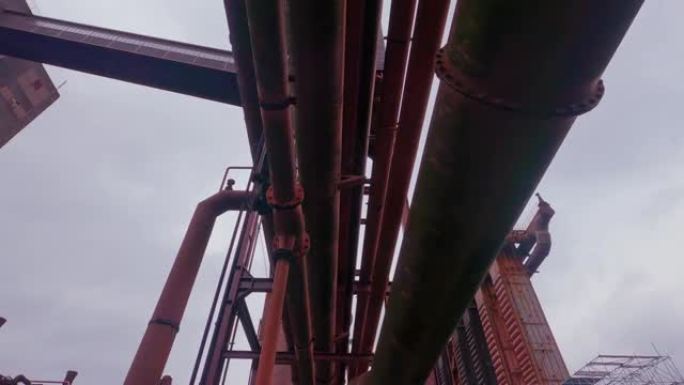 工业区的红色管道，从下面的管道和管道桥的支撑上的抽象视图