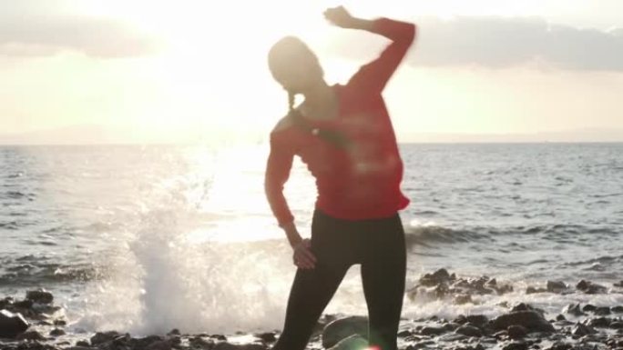 女人在日落时在海边锻炼前做伸展运动