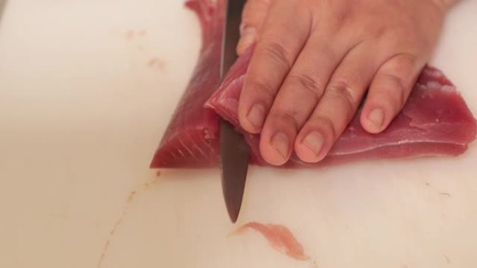 用锋利的寿司刀切开新鲜的金枪鱼。