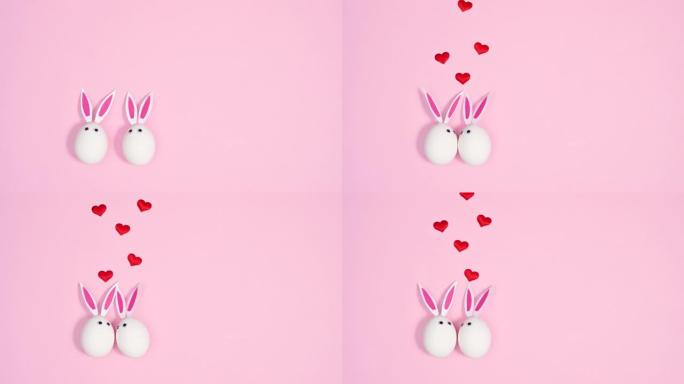 两个白色的鸡蛋与兔耳的爱心花在柔和的粉红色背景上飞翔。爱情概念。春假。停止运动