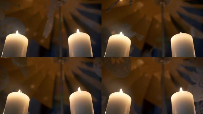 降临节白色蜡烛上的旋转装饰由胶合板制成，描绘天使或圣诞树