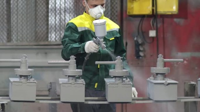 金属零件的粉末底漆涂层。穿着防护服的工人在工厂的金属产品结构上喷洒枪中的粉末涂料。