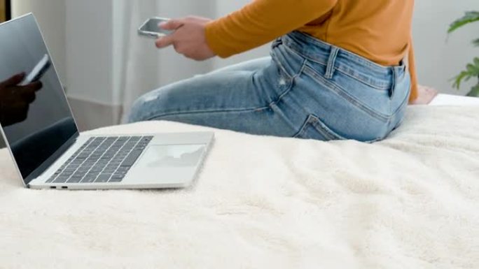 4K 50fps，一名身穿黄色长袖衬衫的亚洲女子，坐在白色床上，旁边放着一台笔记本电脑，焦急地将手机