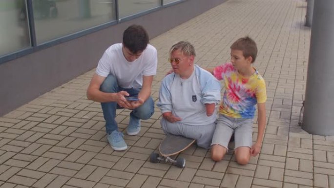 一个残疾人坐在滑板上，周围都是用手机的朋友。