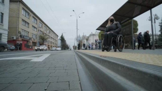 有身体残疾的妇女，坐轮椅在公交车站等车