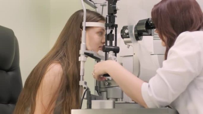 眼科医生用现代设备检查青少年的视力。医生用生物显微镜检查眼睛。在医疗设备的帮助下检查眼睛结构的女医生