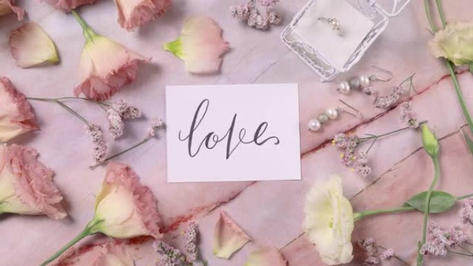 粉色花朵附近大理石桌子上的爱情卡俯视图放大