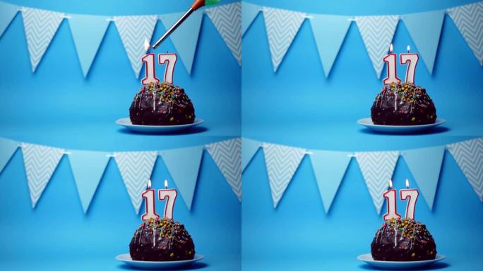 蓝色背景上有十七、十七号燃烧蜡烛的巧克力生日蛋糕。复制空间。文本的位置